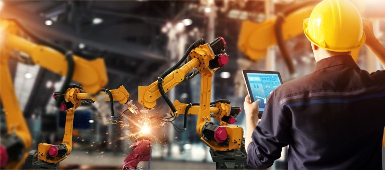 Engineer monitoring robotic arms in an automated factory